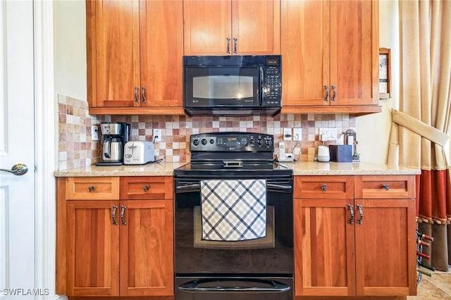 kitchen with backsplash, light stone counters, and black appliances