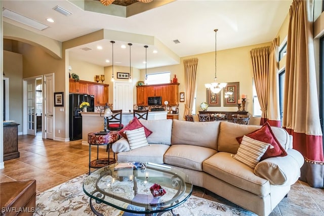 living room with a tray ceiling, a chandelier, and light tile patterned floors