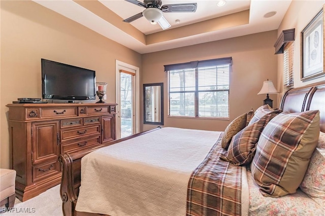 carpeted bedroom featuring ceiling fan and a tray ceiling