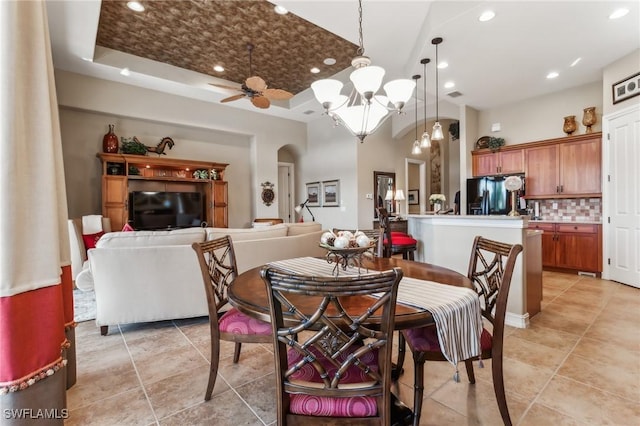 dining space featuring a raised ceiling and ceiling fan with notable chandelier