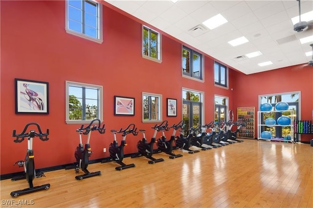 gym with a paneled ceiling, hardwood / wood-style floors, and a high ceiling