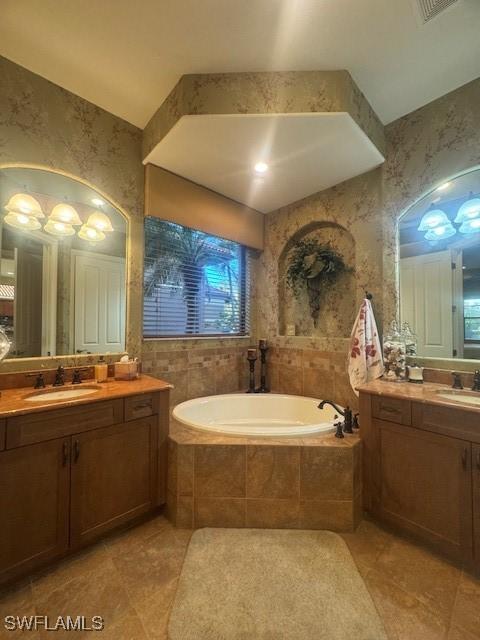 bathroom with vanity, tiled tub, and tile walls