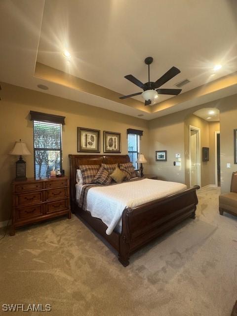 bedroom featuring ceiling fan, a tray ceiling, and carpet floors