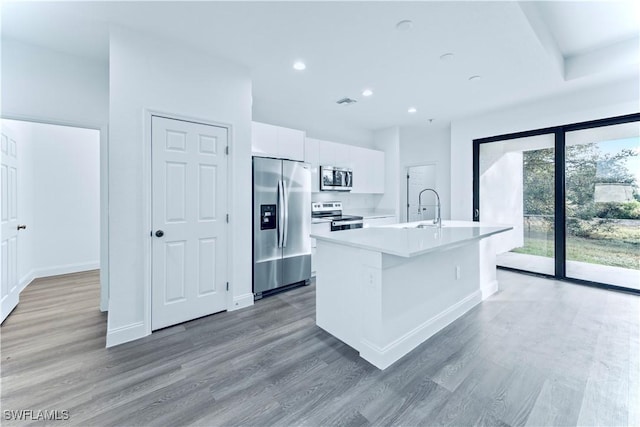 kitchen with wood-type flooring, white cabinetry, a kitchen island with sink, sink, and stainless steel appliances