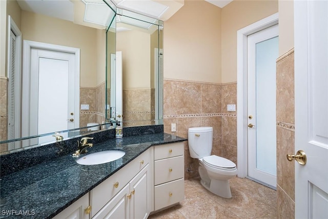 bathroom with tile walls, tile patterned floors, vanity, and toilet