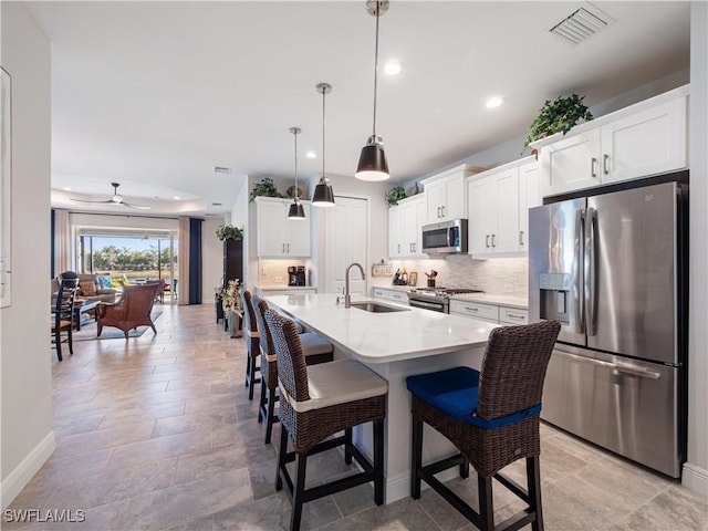 kitchen with white cabinets, stainless steel appliances, a breakfast bar area, and pendant lighting