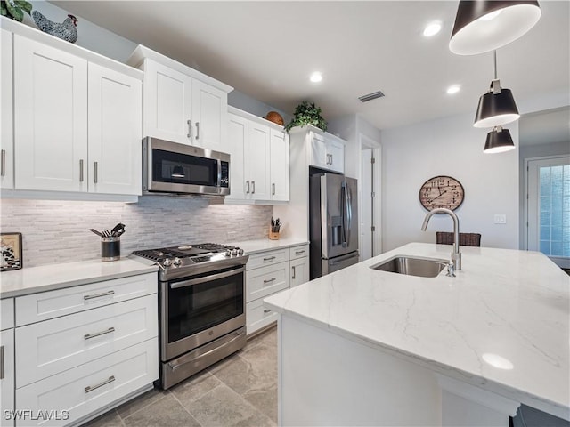 kitchen with white cabinets, sink, pendant lighting, an island with sink, and stainless steel appliances