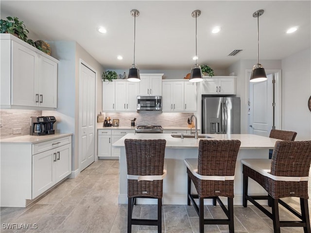 kitchen featuring sink, white cabinetry, hanging light fixtures, and appliances with stainless steel finishes