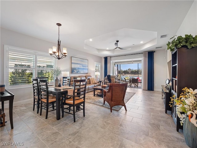 dining space featuring a chandelier, a raised ceiling, and a healthy amount of sunlight