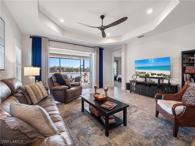 living room with ceiling fan and a tray ceiling