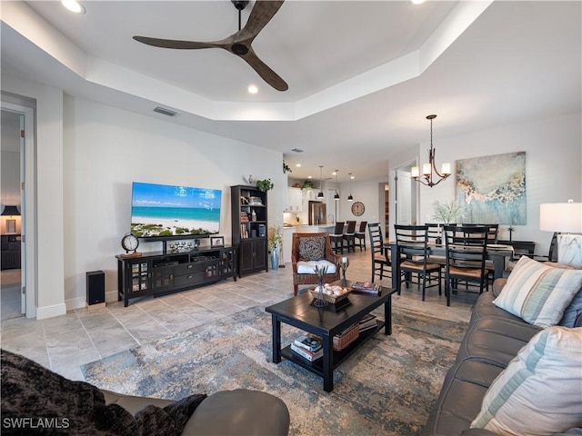 living room featuring ceiling fan with notable chandelier and a tray ceiling