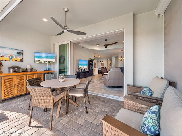 dining space featuring ceiling fan with notable chandelier and a raised ceiling