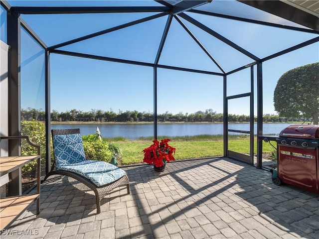 view of patio with area for grilling, a lanai, and a water view