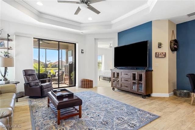 living room featuring wood-type flooring, a tray ceiling, and a wealth of natural light