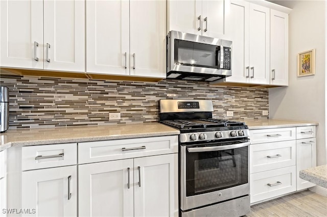 kitchen featuring white cabinetry, tasteful backsplash, light hardwood / wood-style flooring, appliances with stainless steel finishes, and light stone countertops