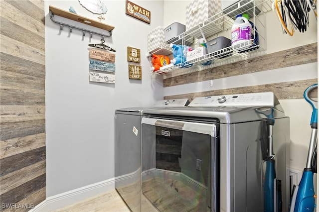 laundry area with washer and dryer and wood walls