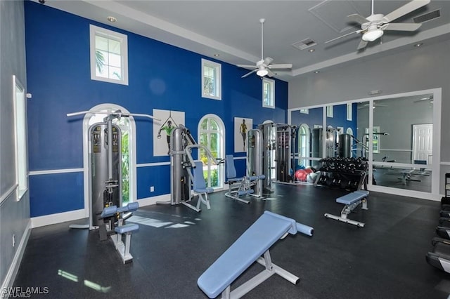 exercise room featuring ceiling fan and a towering ceiling