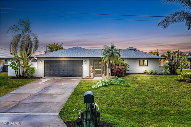 ranch-style home with an attached garage, a lawn, concrete driveway, and stucco siding