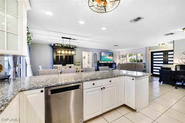 kitchen with light tile patterned floors, light stone countertops, white cabinetry, and stainless steel dishwasher