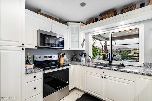 kitchen featuring appliances with stainless steel finishes, a sink, glass insert cabinets, and white cabinets