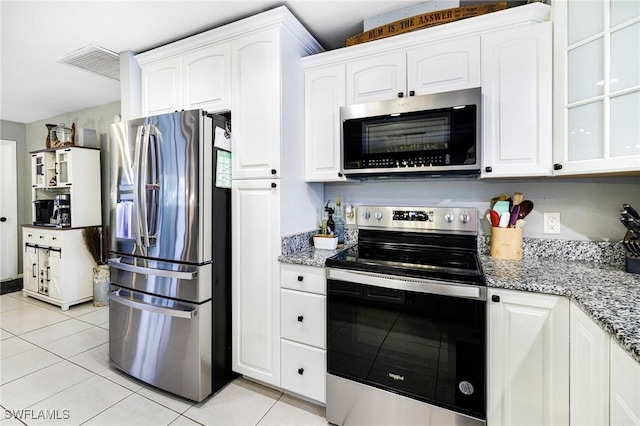 kitchen featuring stone countertops, light tile patterned floors, white cabinetry, and appliances with stainless steel finishes