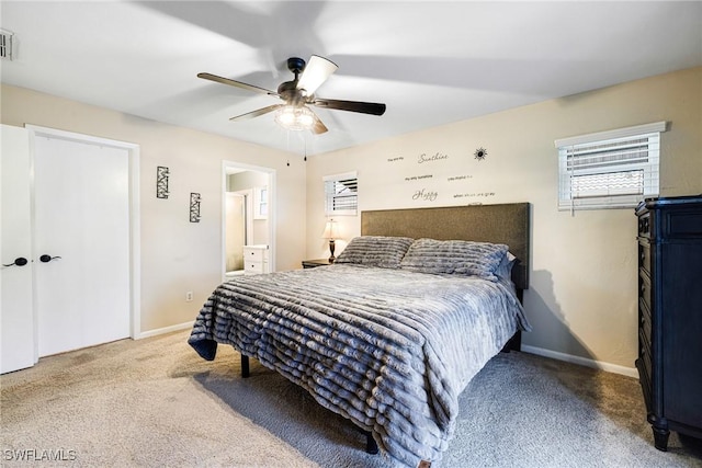 carpeted bedroom with ceiling fan, ensuite bathroom, visible vents, and baseboards