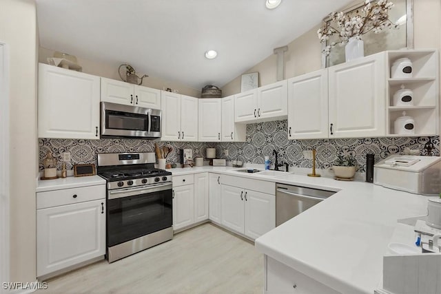 kitchen featuring light hardwood / wood-style floors, vaulted ceiling, sink, white cabinets, and stainless steel appliances