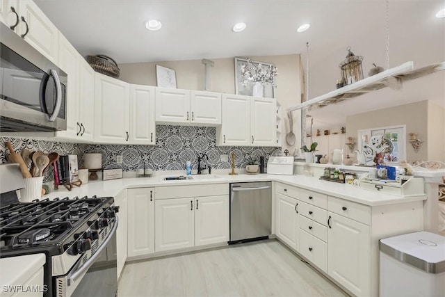 kitchen with kitchen peninsula, sink, white cabinetry, and stainless steel appliances