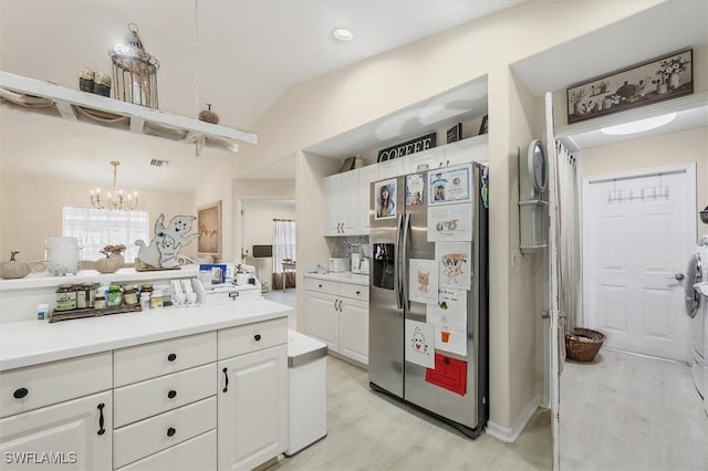 kitchen with light hardwood / wood-style floors, white cabinets, decorative light fixtures, vaulted ceiling, and stainless steel fridge