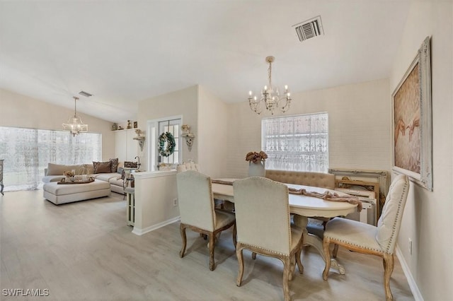 dining space with plenty of natural light, a chandelier, light hardwood / wood-style flooring, and vaulted ceiling