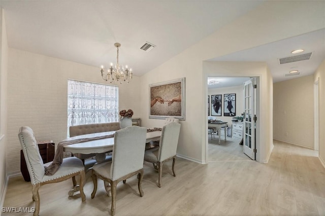 dining space with a notable chandelier, light hardwood / wood-style flooring, and lofted ceiling