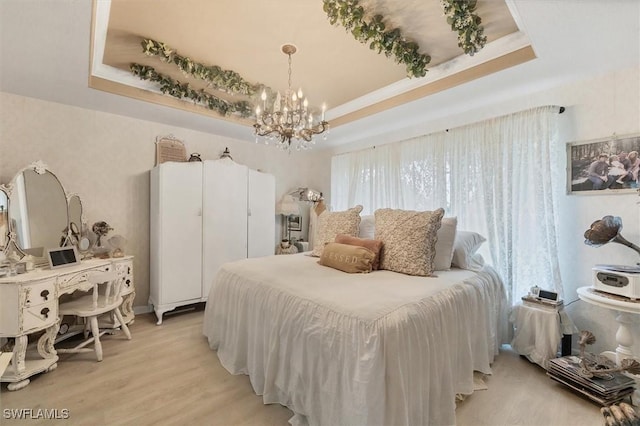 bedroom featuring light hardwood / wood-style flooring, a raised ceiling, and a chandelier