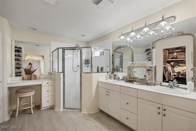 bathroom with wood-type flooring, a shower with door, and vanity