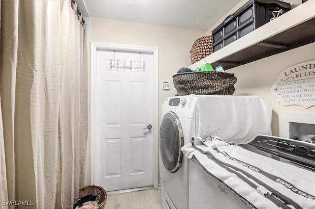 laundry area with light hardwood / wood-style flooring and washing machine and dryer