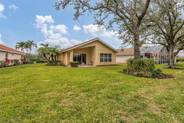 back of property with glass enclosure and a lawn