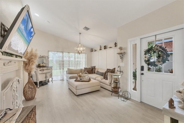 living room with light hardwood / wood-style floors, a notable chandelier, and vaulted ceiling