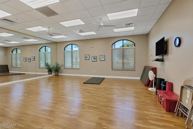 workout area featuring a paneled ceiling, light wood-type flooring, and ceiling fan