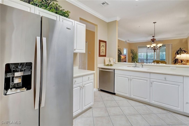 kitchen featuring white cabinets, stainless steel appliances, sink, hanging light fixtures, and ornamental molding