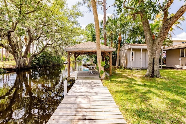 dock area featuring a gazebo, a water view, and a yard