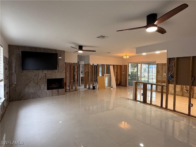 unfurnished living room featuring ceiling fan and a tile fireplace