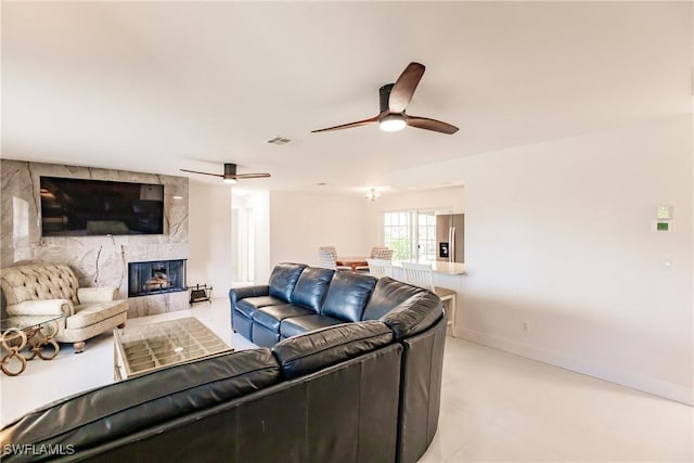 living room with ceiling fan and a fireplace