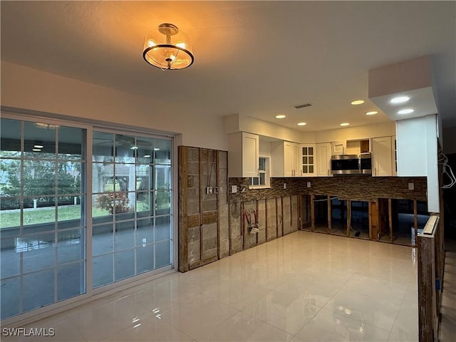 kitchen featuring white cabinets, backsplash, and light tile patterned flooring