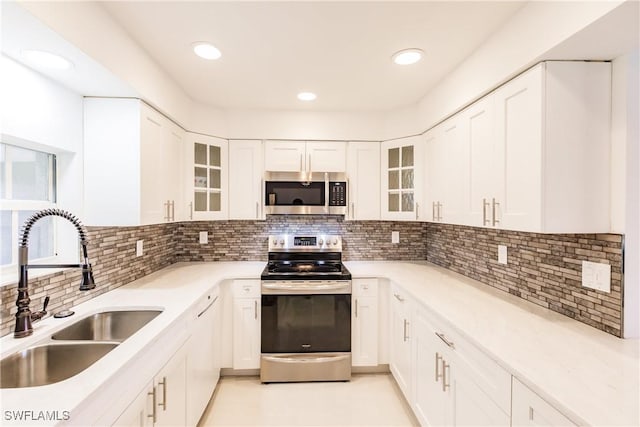 kitchen featuring decorative backsplash, sink, white cabinetry, and appliances with stainless steel finishes