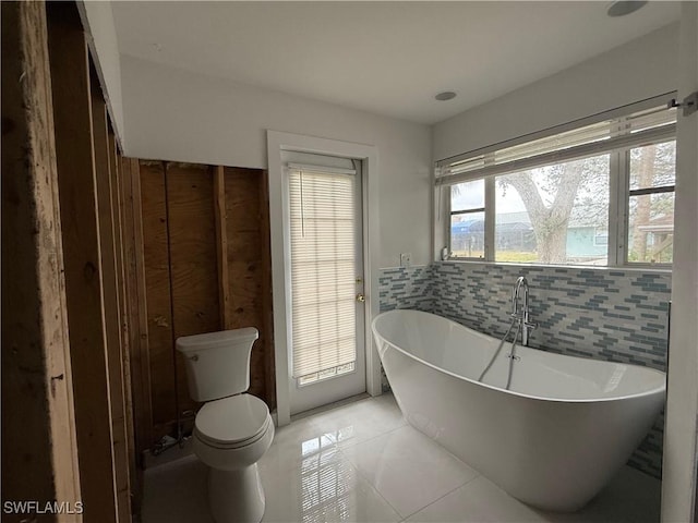 bathroom featuring a tub, tile patterned floors, and toilet