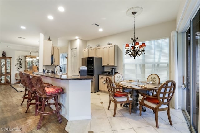 kitchen with decorative light fixtures, stainless steel fridge, a kitchen bar, kitchen peninsula, and an inviting chandelier