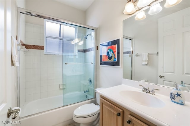 full bathroom with enclosed tub / shower combo, vanity, and toilet