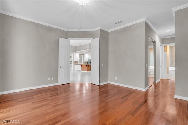 empty room with crown molding and wood-type flooring