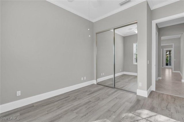 unfurnished bedroom with crown molding, light hardwood / wood-style flooring, a closet, and ceiling fan