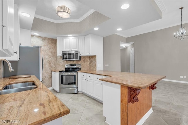 kitchen with sink, appliances with stainless steel finishes, kitchen peninsula, pendant lighting, and white cabinets