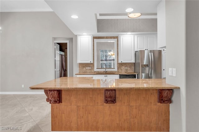 kitchen with sink, stainless steel fridge, light stone countertops, decorative backsplash, and white cabinets